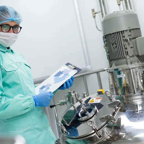 scientist-blue-lab-uniform-stand-near-big-pressure-tank-hold-tablet-with-graphs-look-camera-scaled.webp